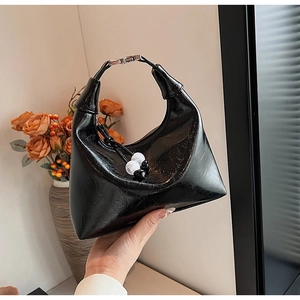 Détail du sac hobo noir verni en forme de lune avec un pendentif décoratif en perles