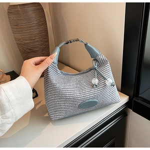 Detail of woven crescent handbag with blue-white texture and silver metallic lock closure