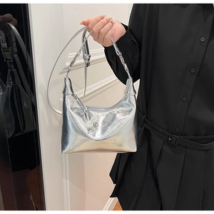 Détail d'un sac à main argenté métallisé avec texture froissée et pendentif boule métallique