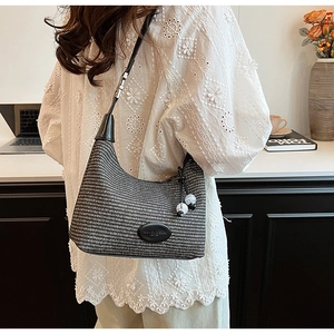 Detailed texture of black and white woven hobo bag with pearl beads and leather strap