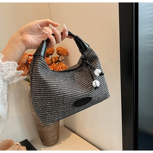 Detail of woven half-moon hobo bag with black leather handle and beaded charm detail