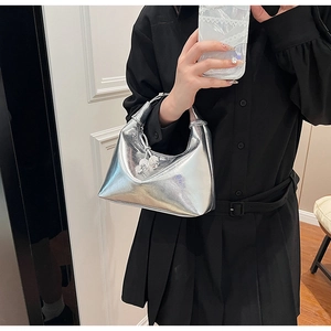 Détail du sac à main argenté métallisé avec poignée nouée et breloque sphérique