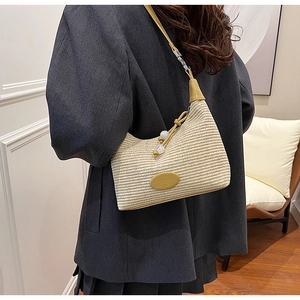 Detailed close-up of beige woven straw shoulder bag with yellow leather strap and drawstring