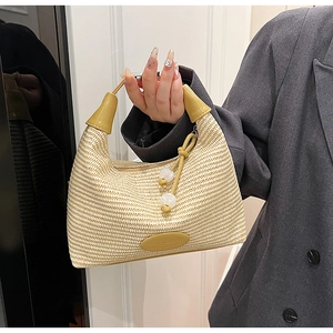 Detail of beige straw crescent bag with leather handle and pearl charm accessory