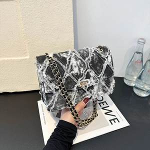 Sac bandoulière en denim noir et blanc matelassé avec bords effilochés et chaîne dorée