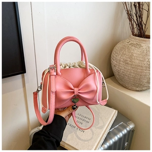 Pink bow handbag with cream drawstring and heart charm on a detachable shoulder strap