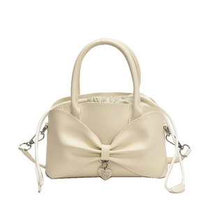 Fashionable beige bow handbag with drawstring pouch and heart charm on white background