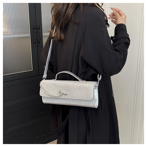 Borsa a spalla plissettata argento con fibbia a nodo, indossata da modella in casa
