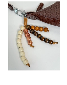 Detail of dark brown woven bag with silver buckle and bohemian wooden bead pendant