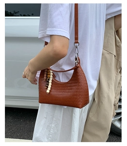 Brown woven hobo bag detail with adjustable leather strap and wooden bead tassel accessory