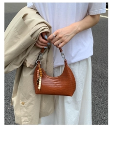 Detail of caramel brown woven leather hobo bag with vintage wooden bead pendant accessory