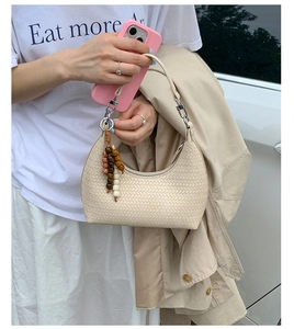 Detail of beige woven hobo bag with bohemian wooden bead tassel and silver zipper