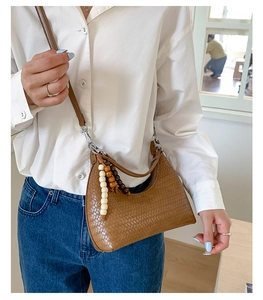 Detail of brown woven shoulder bag with unique wooden beaded charms and zipper closure