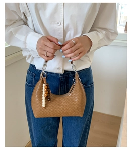 Detailed texture of brown woven hobo bag with colorful wooden beads on model