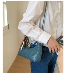 Detail of teal woven shoulder bag with vintage wooden bead tassel and zipper closure