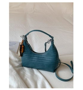 Détail du sac croissant tressé bleu sarcelle avec breloque en perles de bois et métal argenté