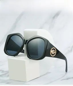 Vue détaillée des lunettes de soleil noires avec décor de branche en feuille dorée