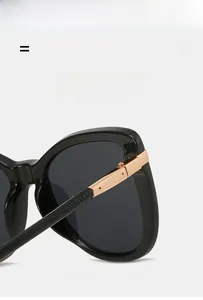 Close-up of golden metal hinge on black cat eye sunglasses with sleek polished frames