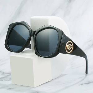 Lunettes de soleil géométriques noires chic avec design évidé doré sur marbre