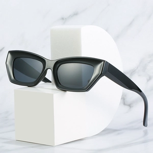 Lunettes de soleil œil de chat noires pour femmes avec verres foncés sur socle blanc