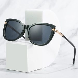 Stylish cat-eye sunglasses with black frame and gold metal accents on marble platform