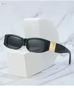 Detail of square black sunglasses featuring gold diamond metal hinge on white marble