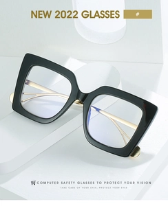 Detail of cat-eye glasses with black frames and gold curved metal temples on white podium