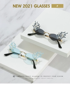 Detail of flame-shaped sunglasses featuring embedded pearls and gold-tone metal bridges