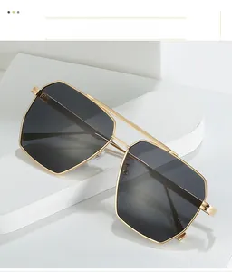 Detail of gold metal double bridge sunglasses with gradient lenses on white display
