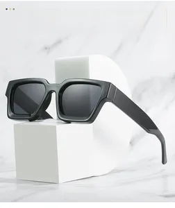 Detail view of stylish thick black square frame sunglasses on minimalist display stand