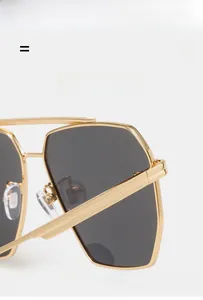 Detailed close-up of golden metal double-bridge sunglasses with polarized grey lenses