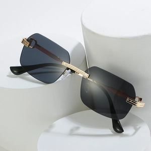 Frameless sunglasses with grey gradient lenses and gold metal frame on white pedestal
