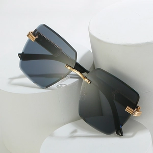 Frameless square sunglasses with grey gradient lenses and gold metal details on a stand
