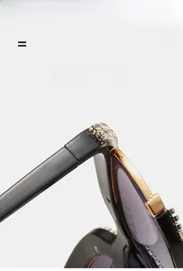 Detail of rhinestone hinges on black and gold oversized fashion sunglasses with purple lenses