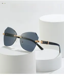 Close-up of frameless cat-eye sunglasses with gradient grey lenses and gold-black temples