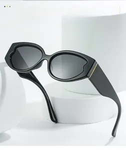 Detail of black oval sunglasses featuring thick frames and golden metal temple accents