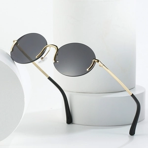 Lunettes de soleil ovales rétro minimalistes avec verres gris et monture dorée sur socle
