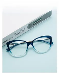 Macro view of blue gradient cat-eye frame with slim gold metal temples on a desk