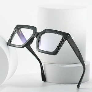 Lunettes carrées noires surdimensionnées avec monture texturée sur socle blanc