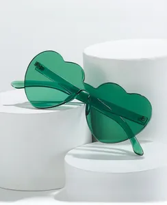Detail view of green heart-shaped frameless sunglasses on white geometric pedestals