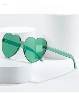 Detailed close-up of green heart-shaped rimless sunglasses on white pedestal display