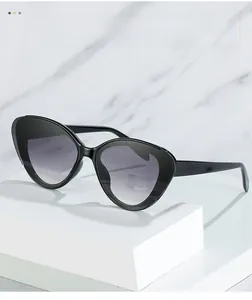 Detail of black cat-eye sunglasses with gradient lenses on a white display stand