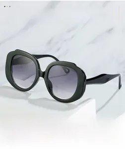 Detail of black oversized sunglasses with gradient lenses and circular temple cutouts