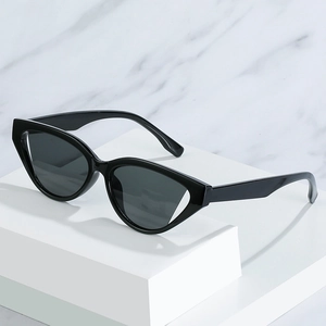 Classic black cat-eye sunglasses with dark grey lenses on white marble background
