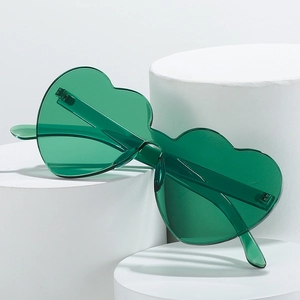 Green heart shaped rimless sunglasses on white pedestals with a modern aesthetic