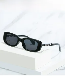 Détail de lunettes de soleil noires carrées avec un design unique de chaîne dorée