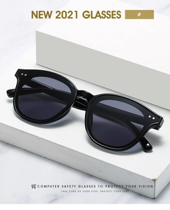 Close-up of black square frame glasses with silver rivets on a marble surface