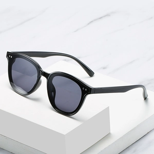 Classic black oversized cat-eye sunglasses with metal rivets on a marble display