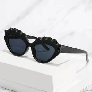 Lunettes de soleil œil de chat noires avec monture festonnée sur fond de marbre