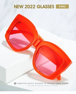 Close-up of bright orange thick frame sunglasses with pink lenses on marble stone